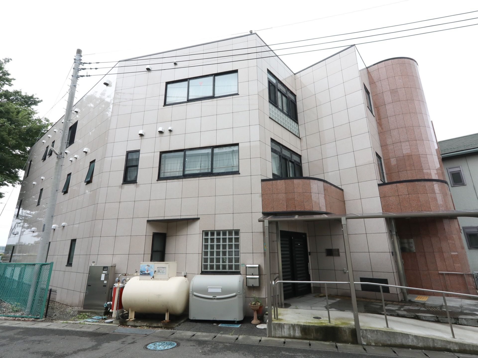 白色と茶色を基調とした外壁を持つ３階建ての施設である。玄関脇には、手すりのついたゆるやかなスロープがある。