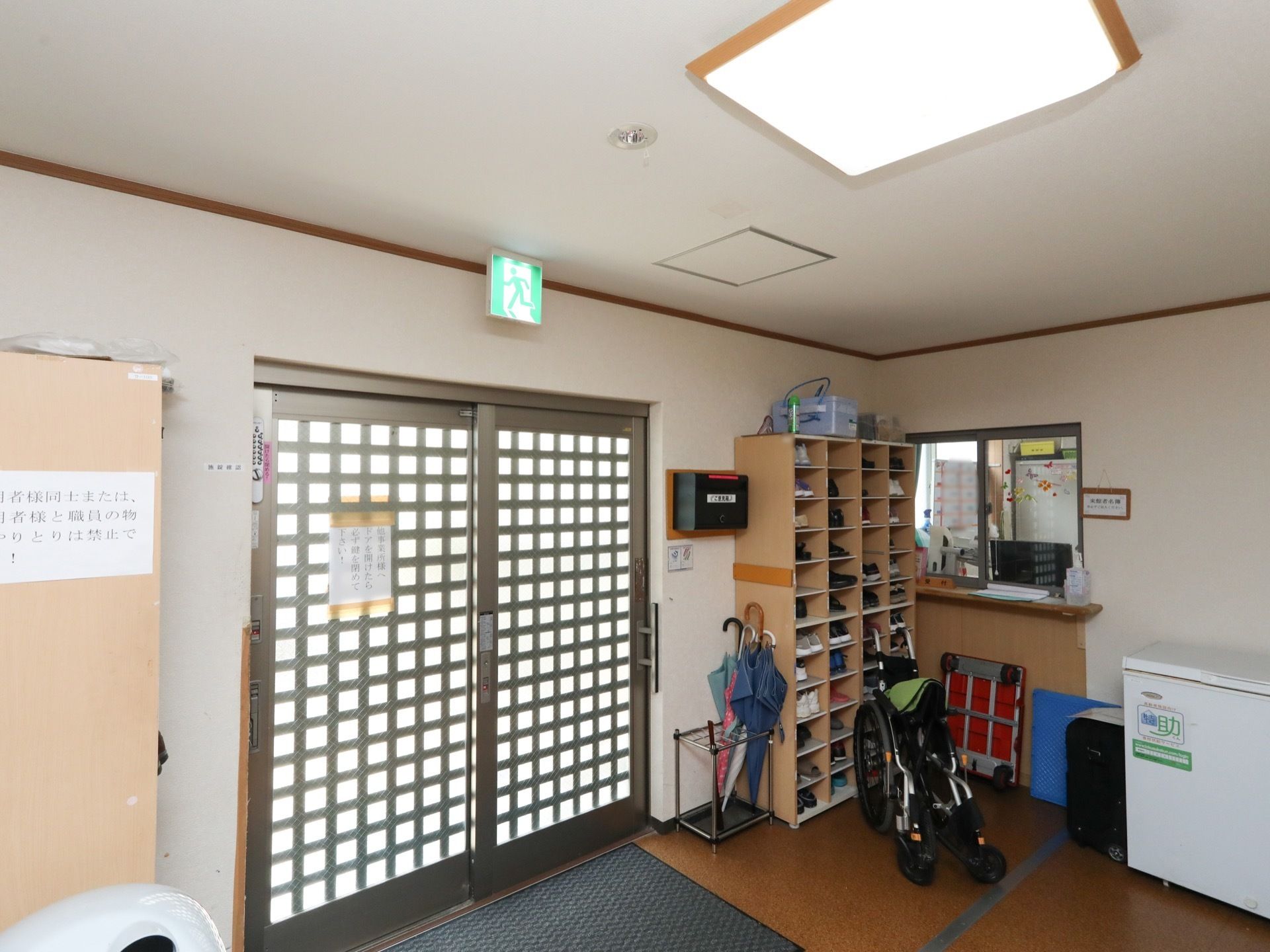格子の入った２枚ドアの玄関となっている。入るとすぐに受付があり、手前に傘立てと靴箱が設置されている。床にはマットが敷かれている。