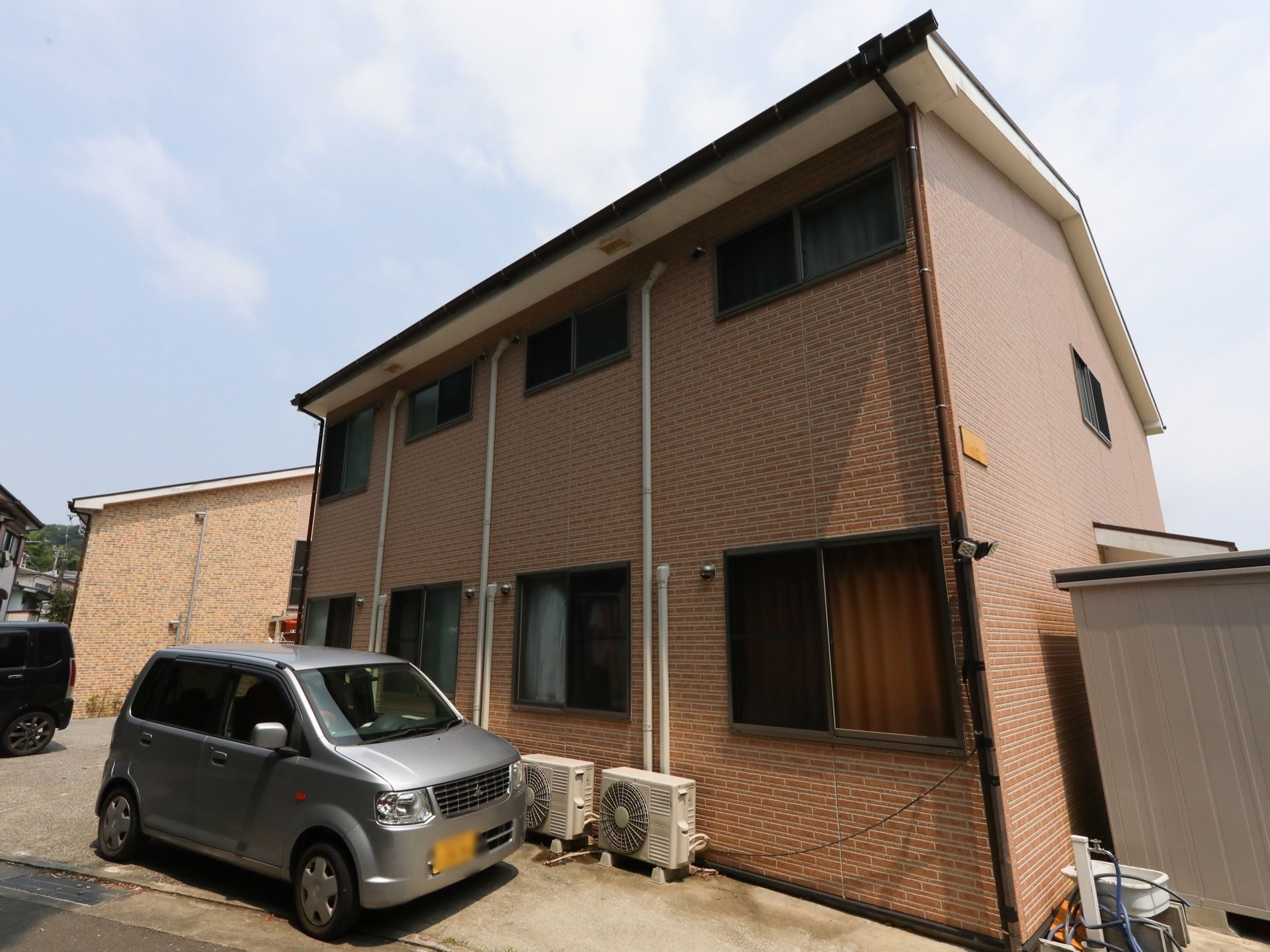 施設の建物は、木造２階建てとなっている。赤茶色の外壁である。建物脇に駐車場があり、車が数台停まっている