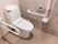 茶色のタイルが床と壁に貼られた個室トイレの図である。温水洗浄便座が設置され、壁に操作パネルが取り付けられている。