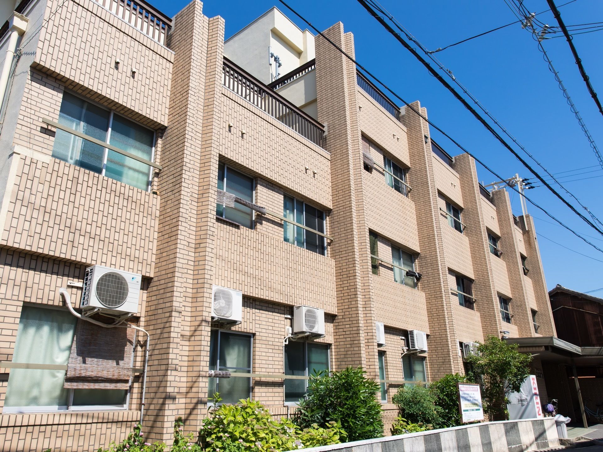 ブラウン色のタイル張りになっている建物である。３階建てになっており、建物の周りには多くの木々が植えられている。