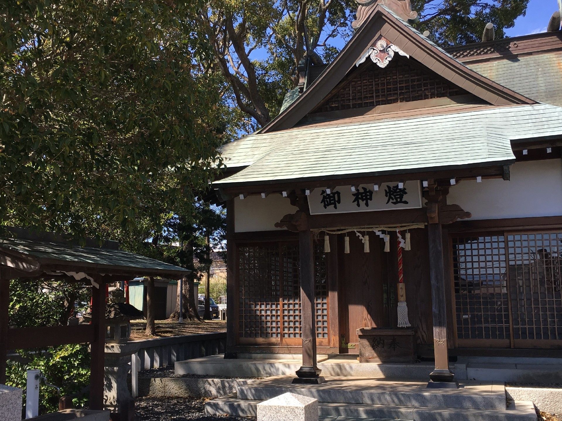 周囲にたくさんの木が生え、静かな境内。屋根の下には「御神燈」と書かれている。