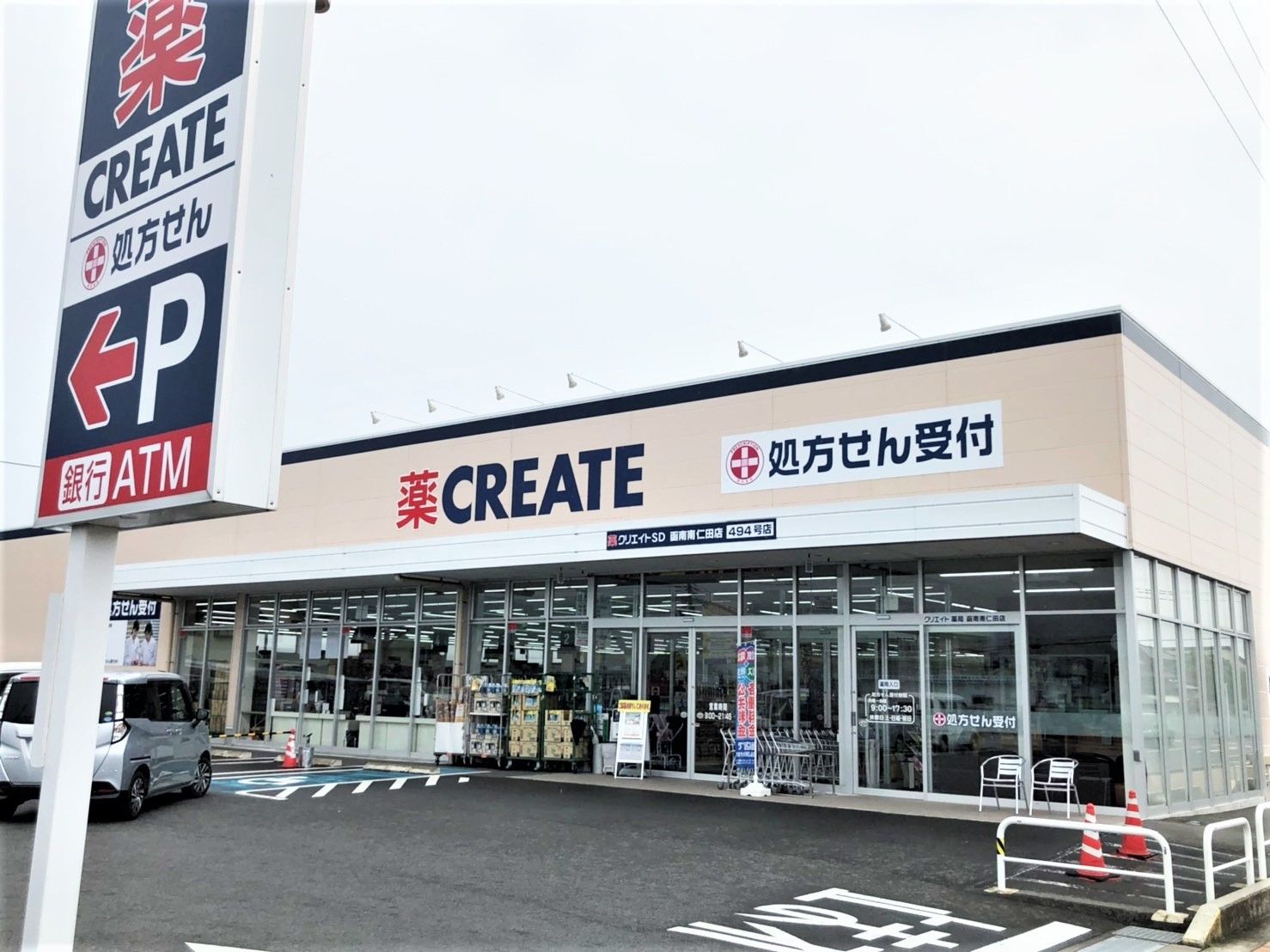 ドラッグストアの前にはカートや特売品が置かれ、店舗前には車いすマークの駐車スペースもある。