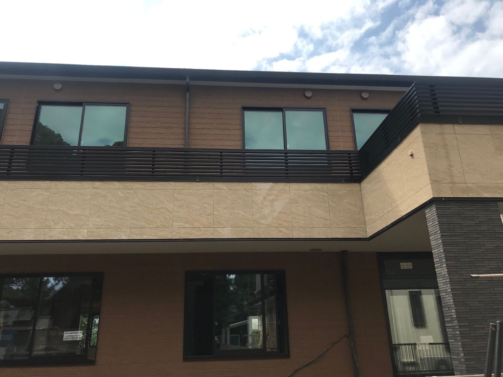 ２階建ての建物はブラウンでまとめられ、玄関部分には屋根もついている。