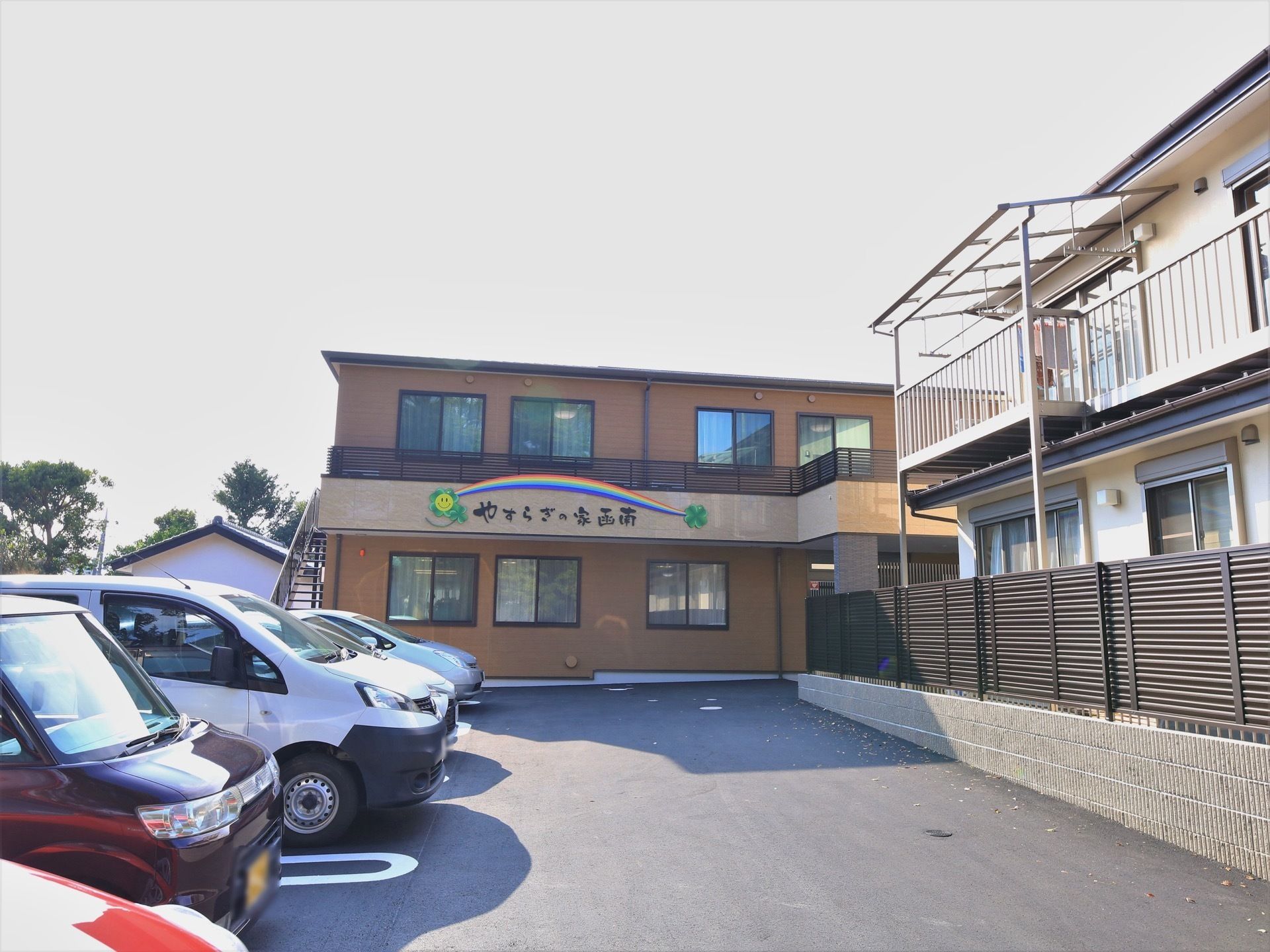 茶色を基調とした外壁の施設である。２階のバルコニーの壁部分に、カラフルな絵柄とともに、施設名称が表示されている。