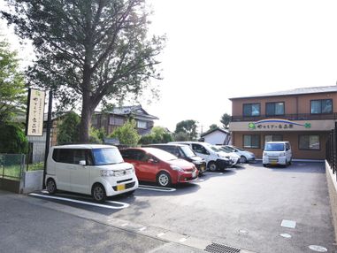 施設の建物は、道路から奥まった所にある。道路から見える正面の外壁に、黒い文字で施設名称が表示されている。