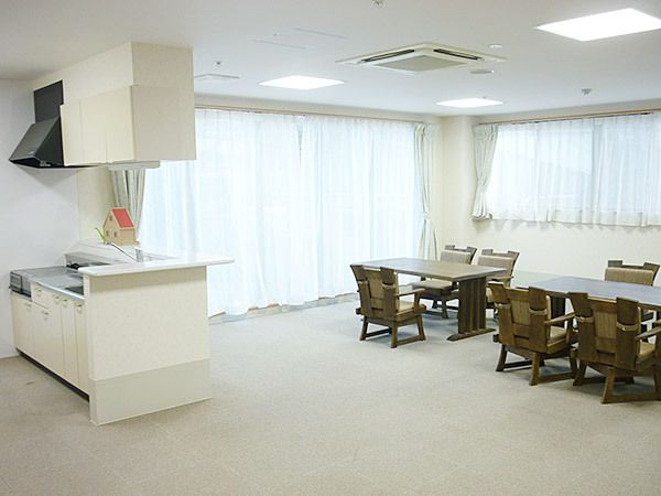 ブラウン系の木製のダイニングテーブルが複数置かれたリビングダイニングには対面式のキッチンもある。