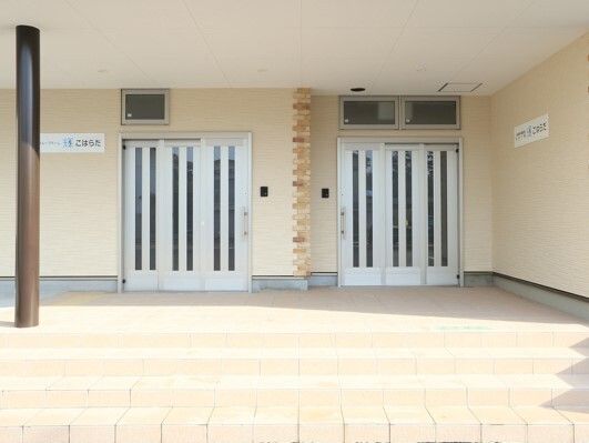 シルバーのドアが二つ並んで設置された玄関。それぞれのドアのそばには事業所名が書かれたプレートがある。