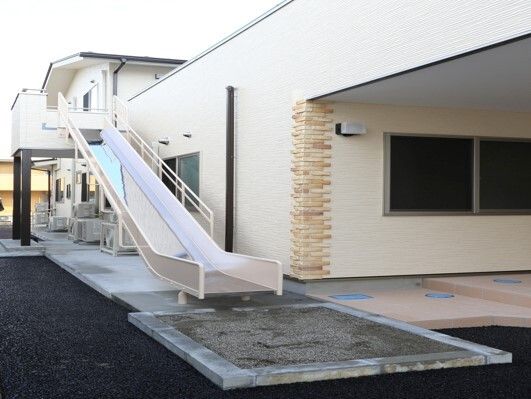 滑り台が設置されたホーム。2階建ての建物はベージュでベランダ部分から滑り台で避難することができる。