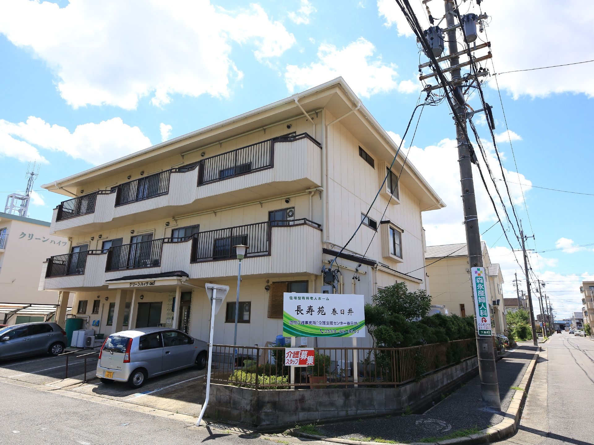 建物前に４台分の駐車スペースがある、３階建ての白い建物