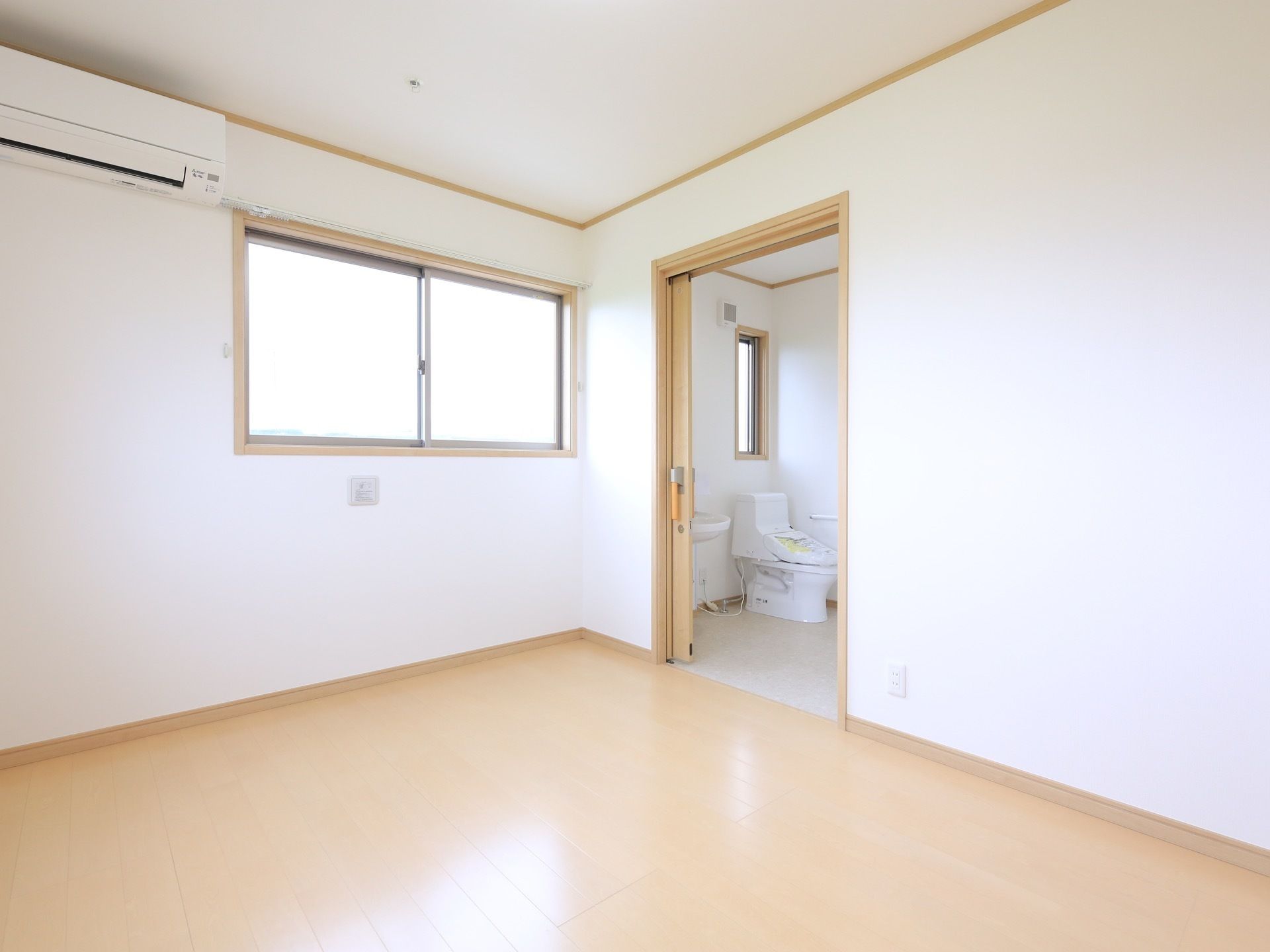 トイレ付の居室は、壁と天井が白で統一され、床は白木風のフローリングである。壁面には窓があり上部にエアコンがある。
