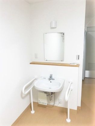 鏡と洗面台がついている施設内の設備の写真。オールバリアフリーの床