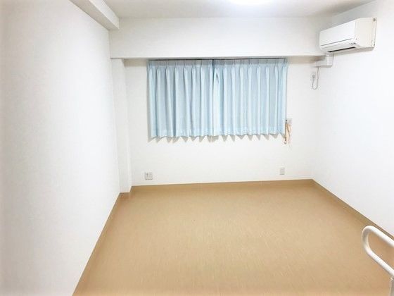 エアコンとカーテンが取り付けてある施設内の居室。入居前の何もない状態