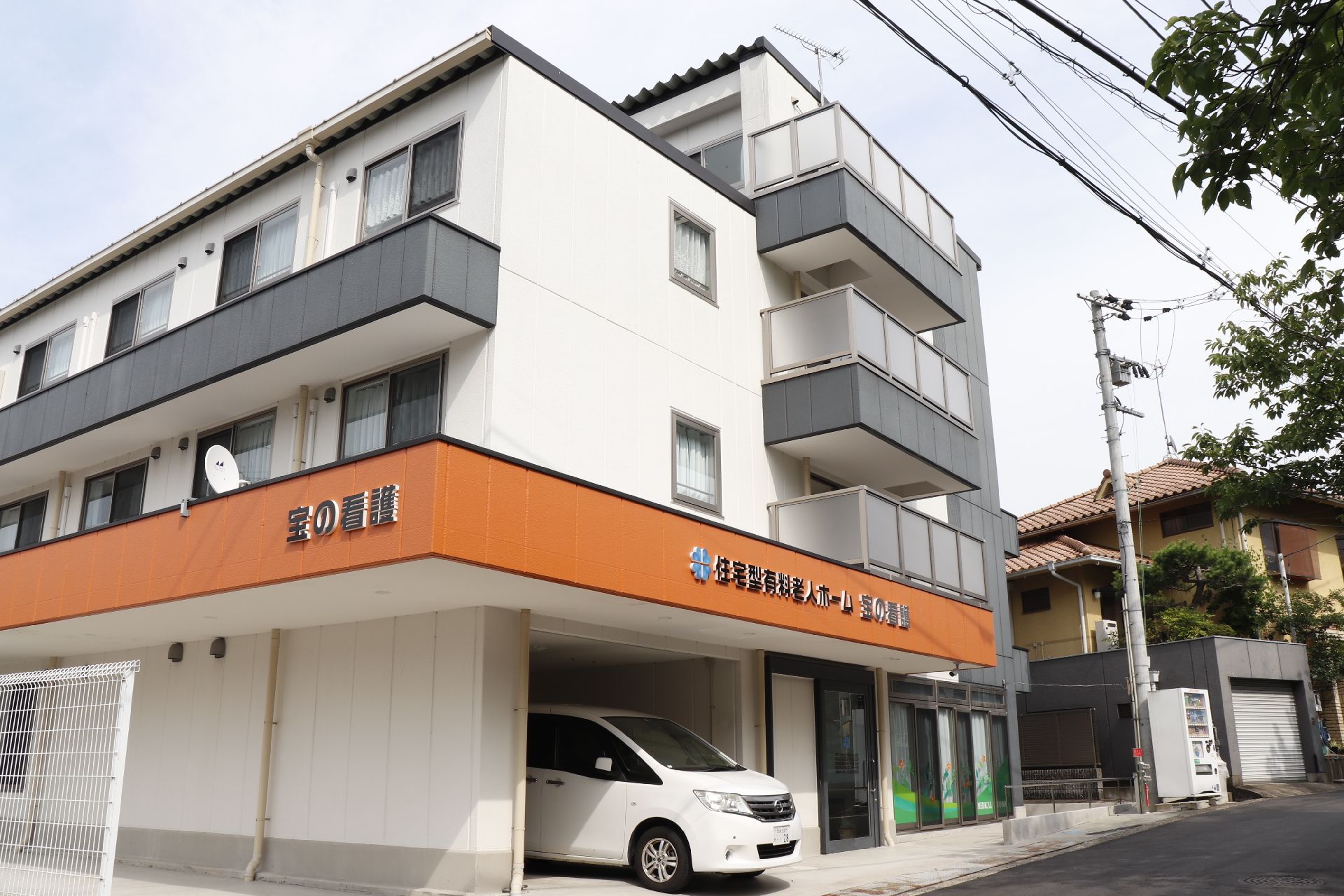 施設の１階部分の屋根には施設名が表示されている。ダークグレー色にベージュ色で書かれており、わかりやすくなっている。