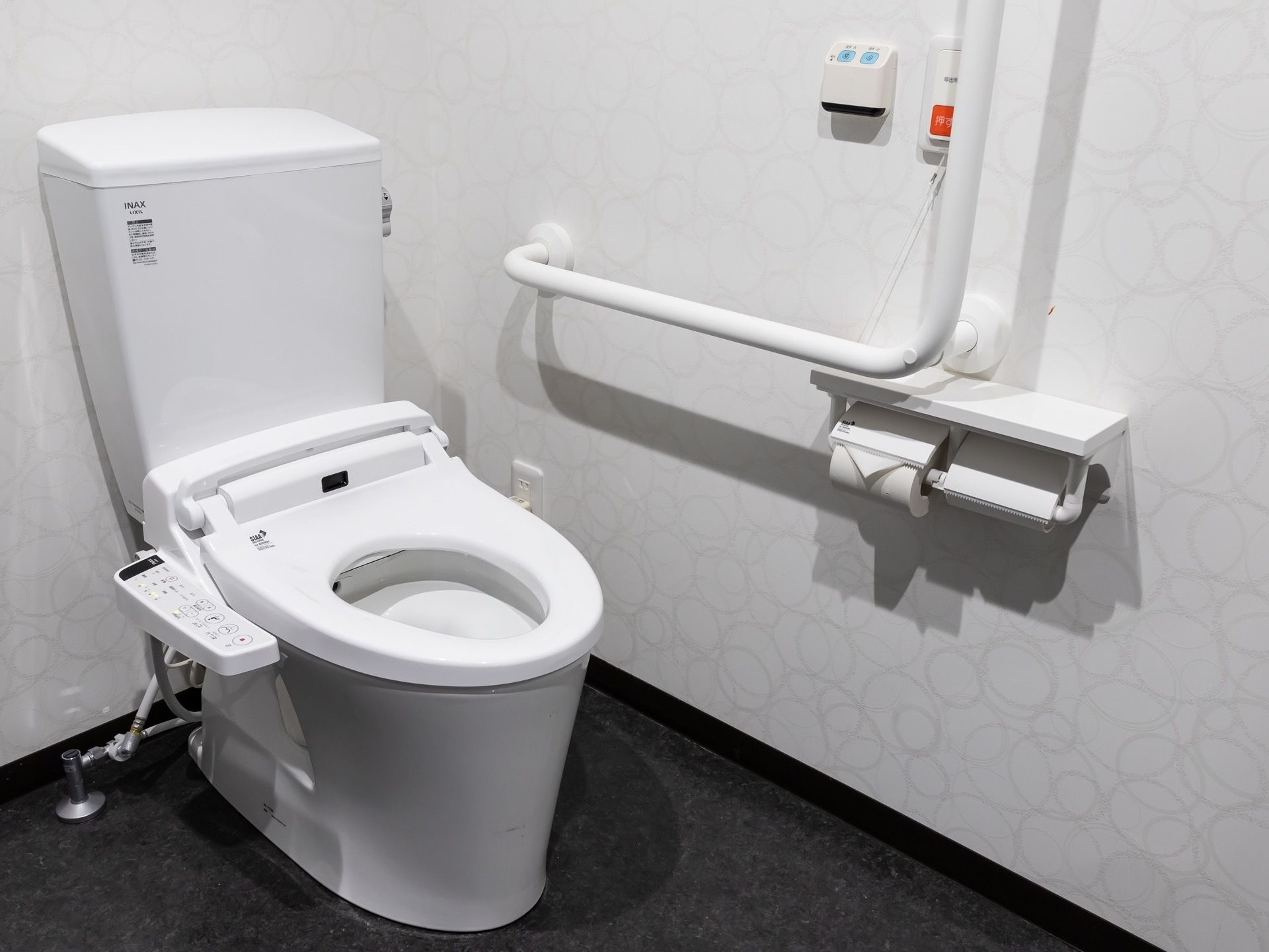 L字型の手すりが設置された、清潔感のあるトイレである。呼び出しベルが完備され、必要に応じて利用することができる。