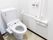 白色の壁で囲まれた空間に、温水洗浄便座付のトイレが置かれている。右側の壁にはL字型の手すりと、非常用ボタンが備え付けられている。