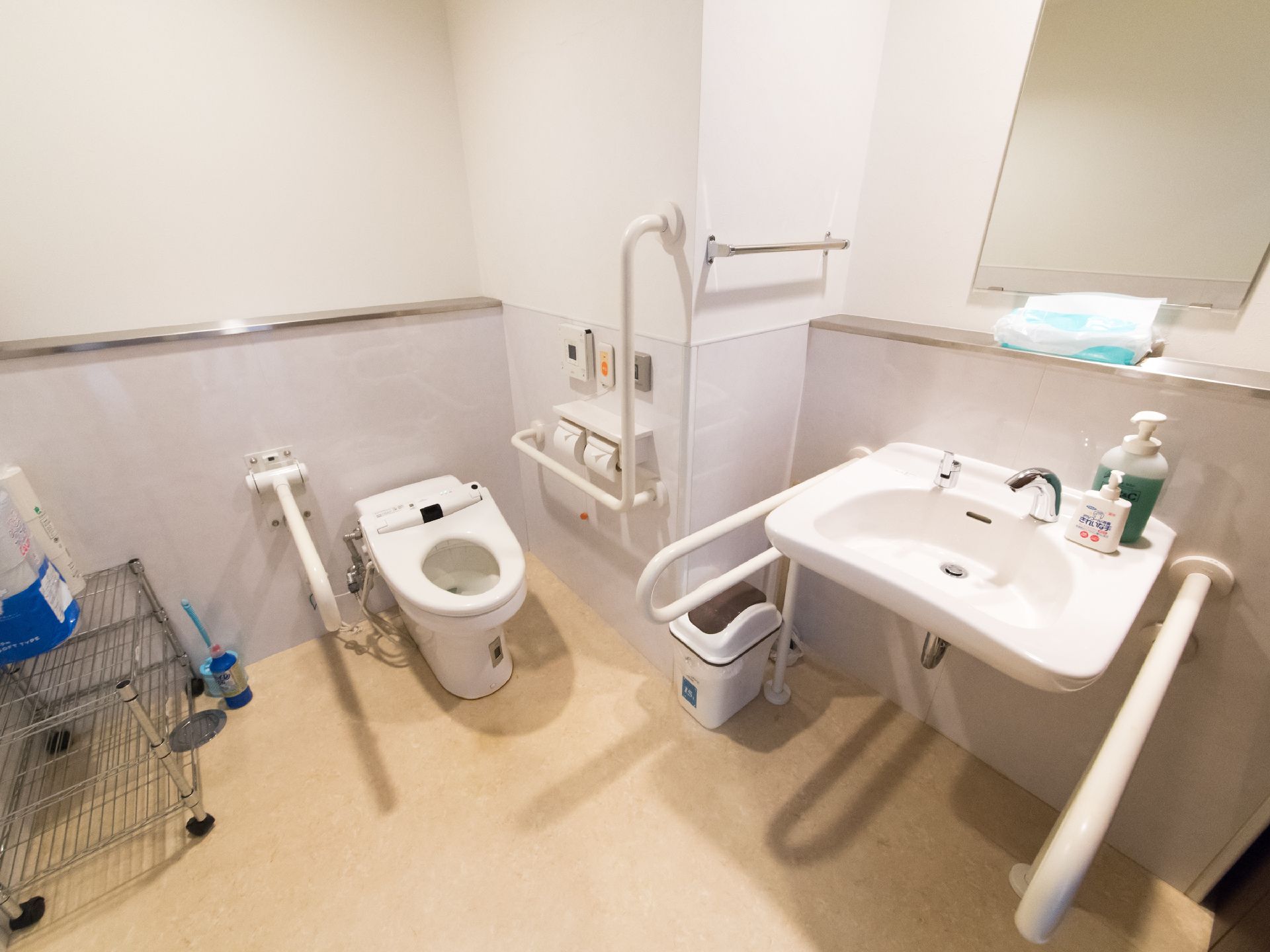 トイレの洗面台の壁には、鏡が取り付けられている。また棚にはペーパータオルがあり、足元にはゴミ箱が用意されている。