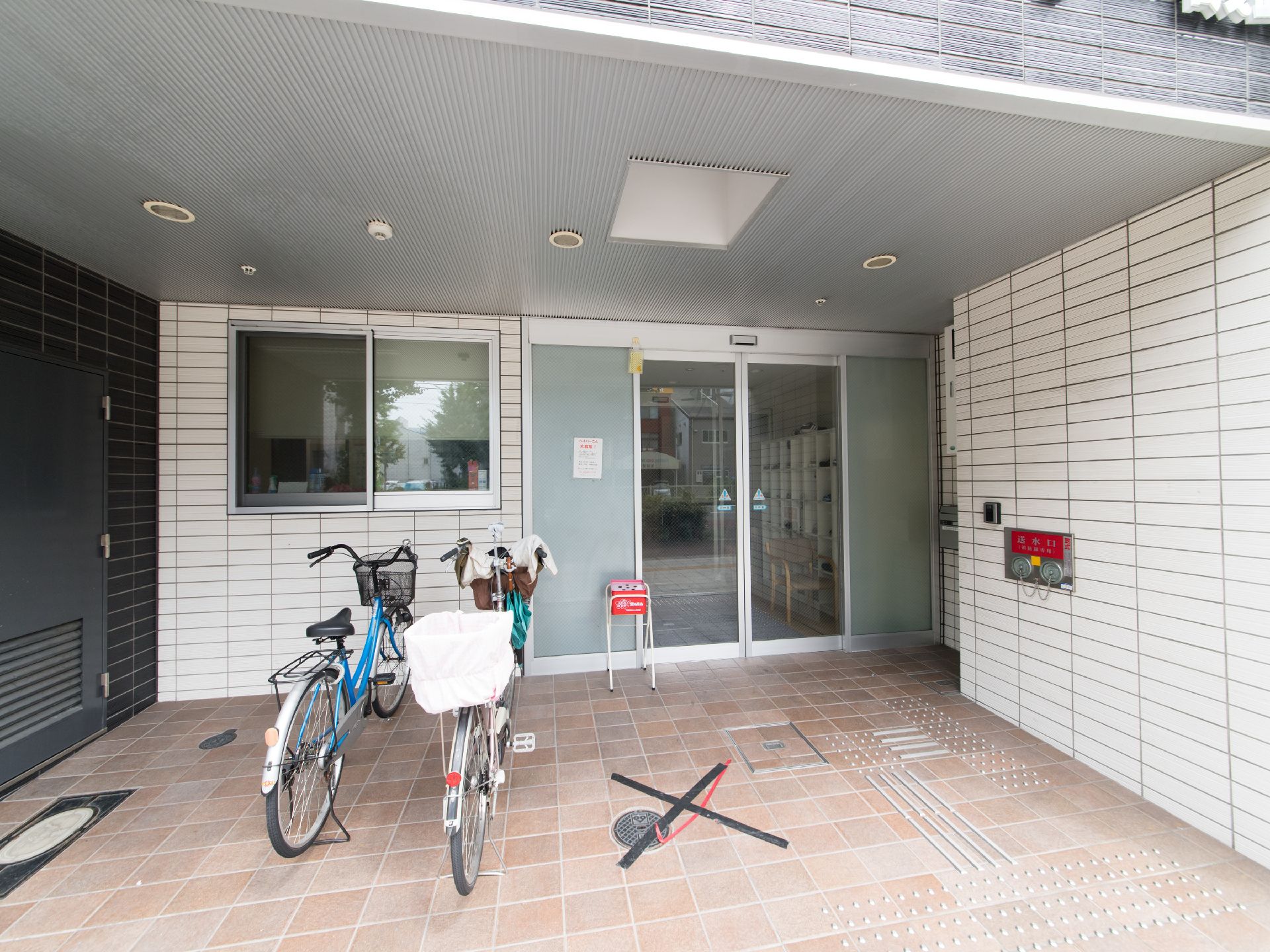 施設のエントランスには、屋根のついた乗降スペースを確保している。入り口にはインターホンがあり、灰皿が置かれている。