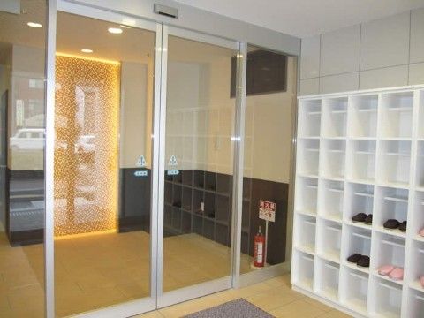 両開きの自動扉のそばに設置される白い個別のオープン靴箱