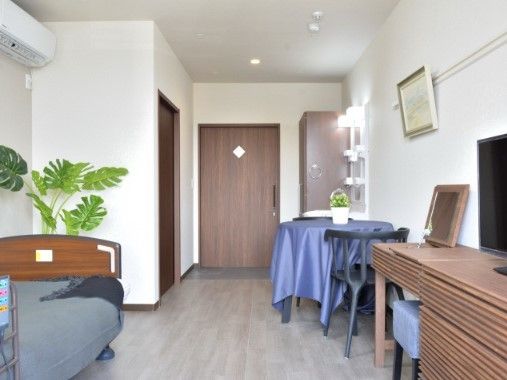 テーブルクロスやベッドカバーがグレーで統一された部屋。家具は木目調