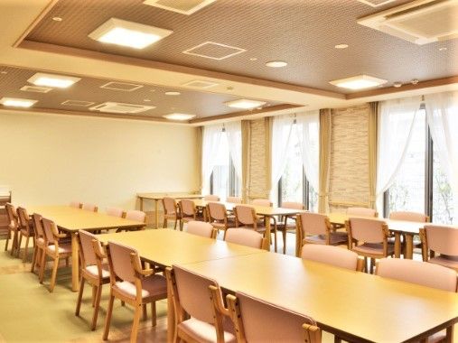 木製のテーブルとピンク色の座面の椅子が並んでいる部屋