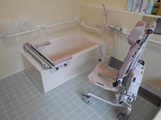 手すりがたくさん設置された浴室にはレールが付いた一人用の浴槽と車いすタイプのリフトが設置されている。