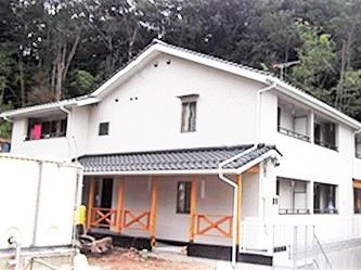大きめの一軒家風の外観の施設。手前にエントランス部分が写っている