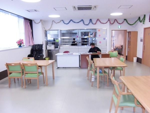 家庭用の4人掛けの机が距離を置いておかれている施設内の食堂・