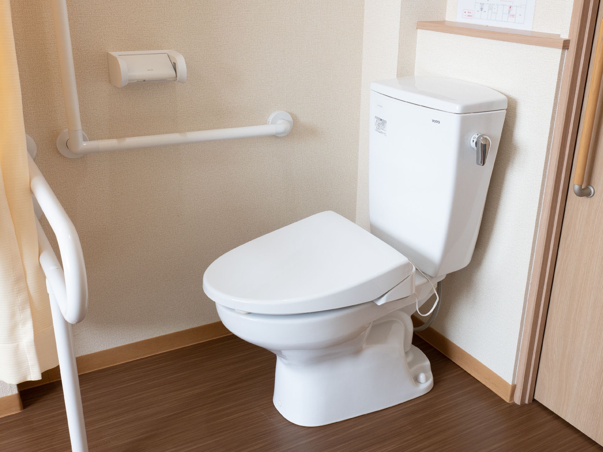 部屋の隅に置かれたL字の手すりとトイレ