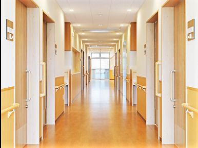 開放的な雰囲気のある廊下の様子。両側の廊下に手すりが取り付けてあり、個室のドアがある