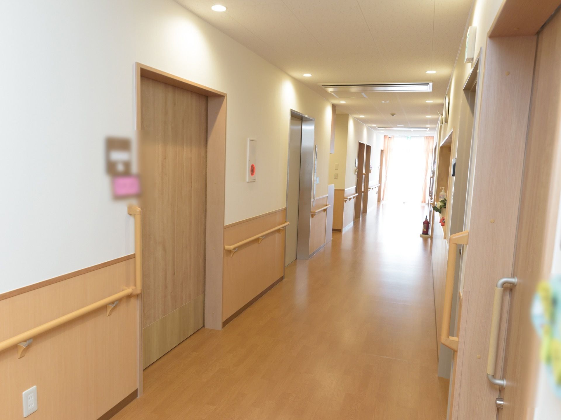 上下が白色とベージュ色に色分けされた壁に手すりがある。壁に非常警報設備がかかっている。