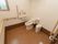 部屋の角に洋式トイレが設置され、前面から側面の壁までグルっと手すりがかかっている。閉じられたすりガラスの小窓がある。