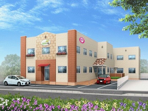 駐車場が付いた2階建ての建物はベージュでまとめられ、玄関には手すり付きのスロープと屋根がある。