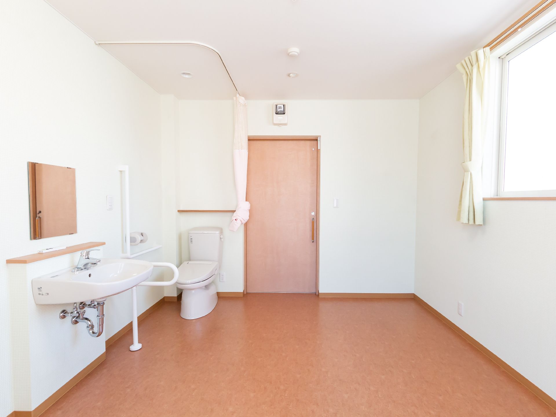 白い壁際に洗面台と洋式便器が配置された部屋