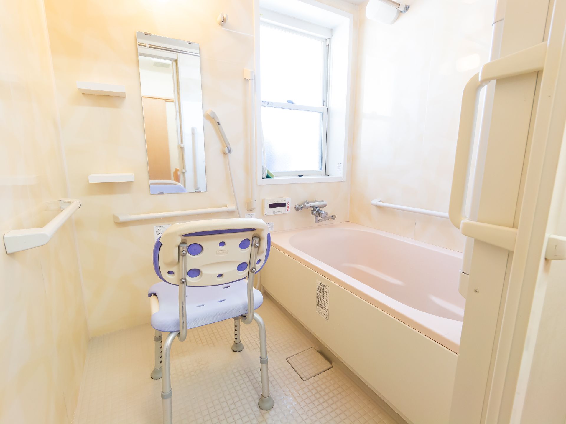 シャワーチェアーが置かれた白い壁の浴室