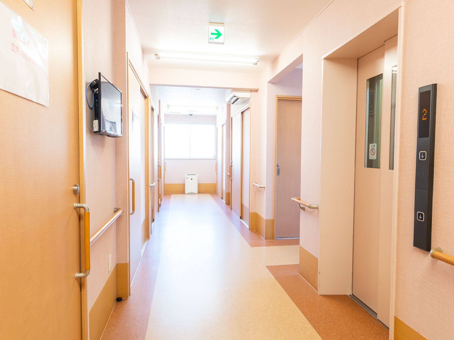 両側の壁に手すりと扉が配置された直線の廊下