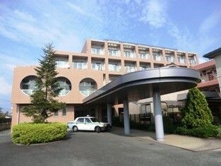 ブラウン系の外壁の大きな建物は日当たりのいい場所に建っている。玄関先には大きな車寄せが付いている。