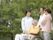 家族やスタッフと出かけている車いすの高齢者。公園のような自然豊かな場