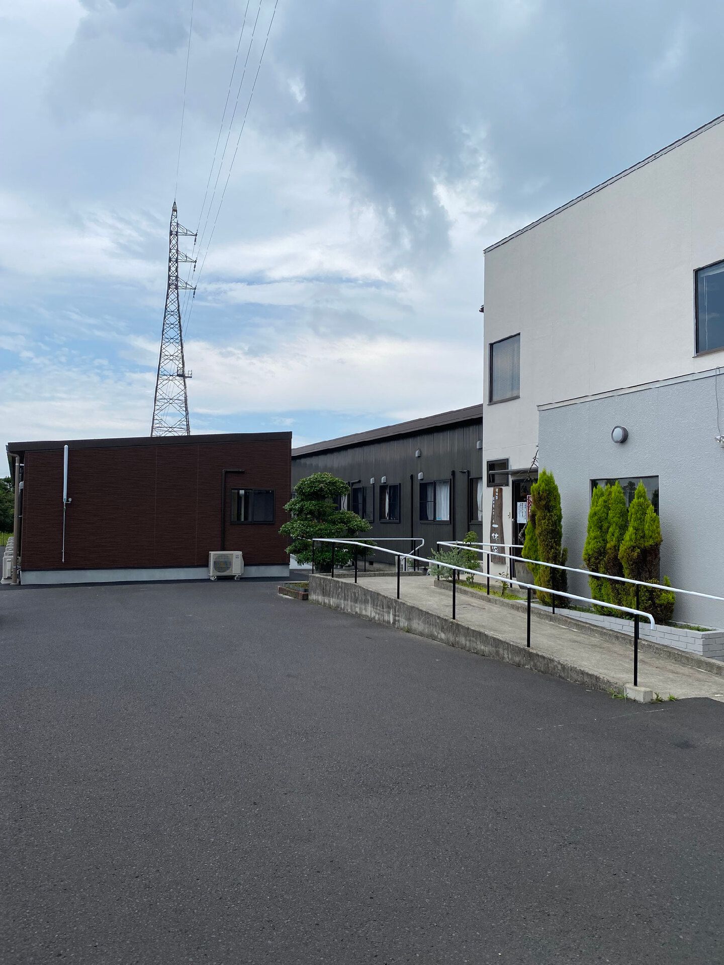 白とグレーでまとめられた２階建ての建物が建つ敷地内には広い駐車場も付いている。
