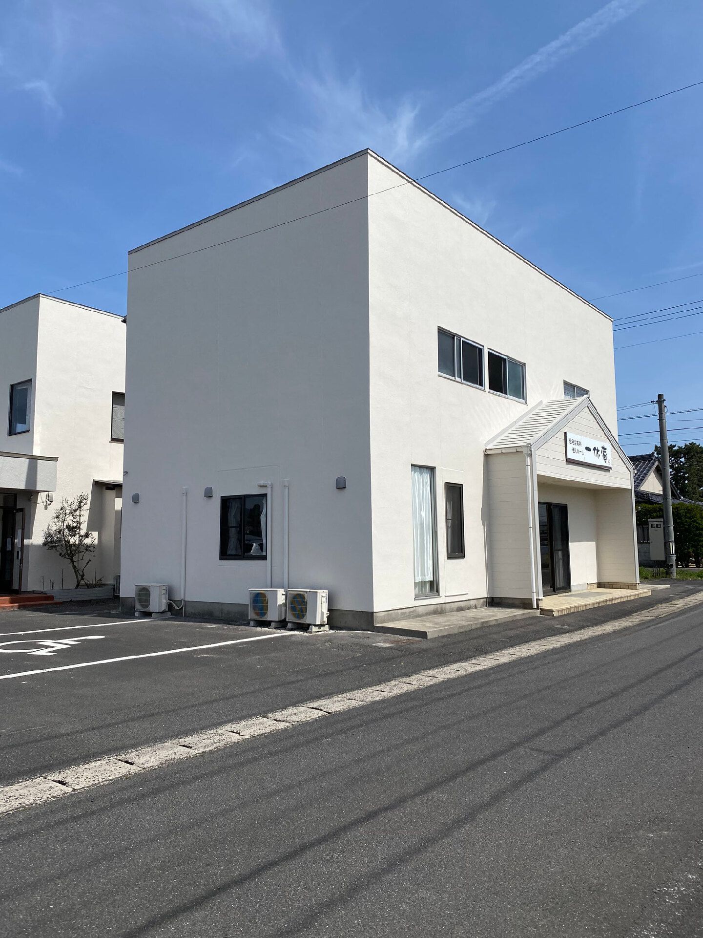 白を基調とした２階建ての建物。玄関部分には三角の屋根が付き、道路に面している。