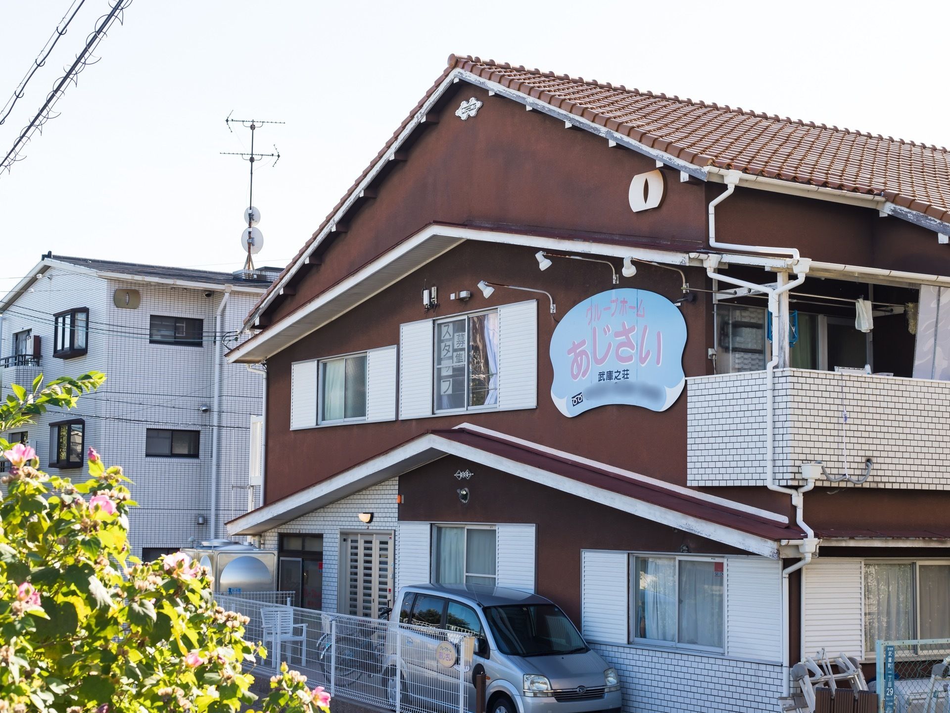 ベランダが完備され瓦屋根が印象的な２階建ての施設である。一般住宅のような外観で駐車スペースがとられている