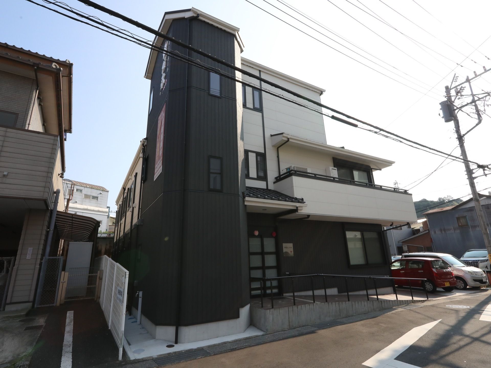 施設は白と黒のシックな外観の２階建てである。建物前に駐車スペースが設けられており、手すり付きのスロープがエントランスに設置されている。