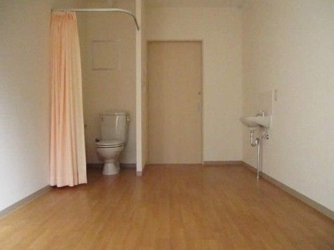 仕切りカーテンで設けられたトイレスペースが設けられたご入居前の居室
