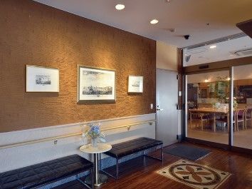 ベンチが二つならんびその前には花が添えられた丸いテーブル、後ろの壁には絵画が数点飾られている。