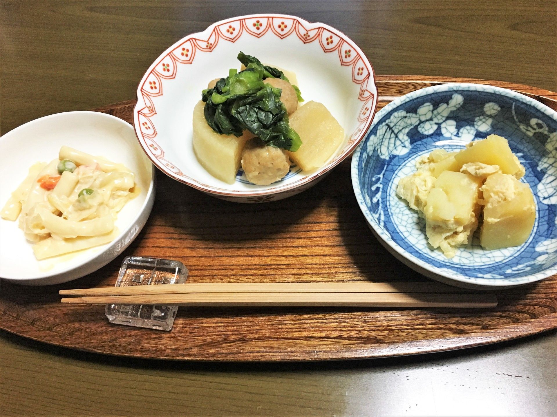 楕円形の木製の盆の上に煮物が２種類とマカロニサラダが乗っている。