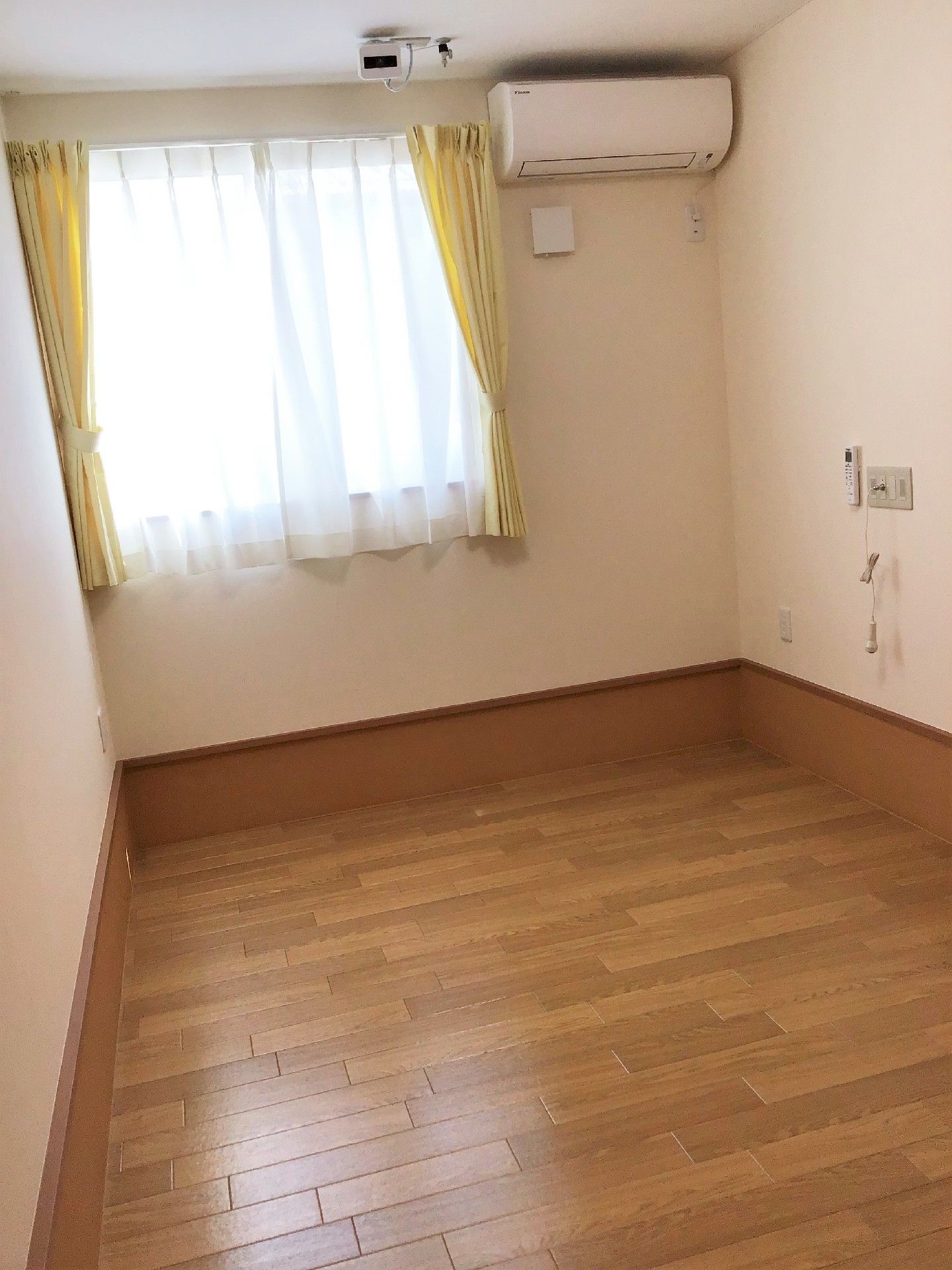 フローリングの居室には何も家具がなく、窓にはカーテンが付いている。