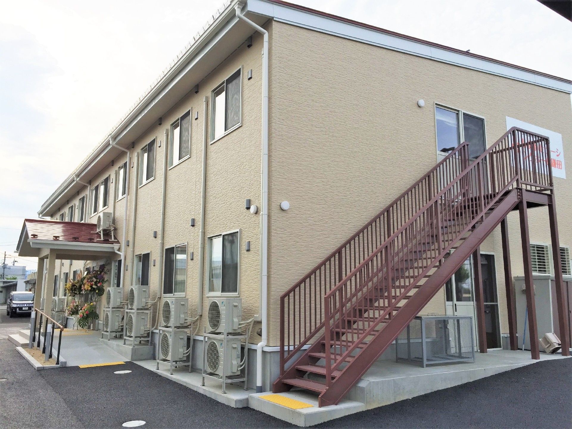 ２階建ての建物はブラウン系で屋外には避難用の階段が設置されている。