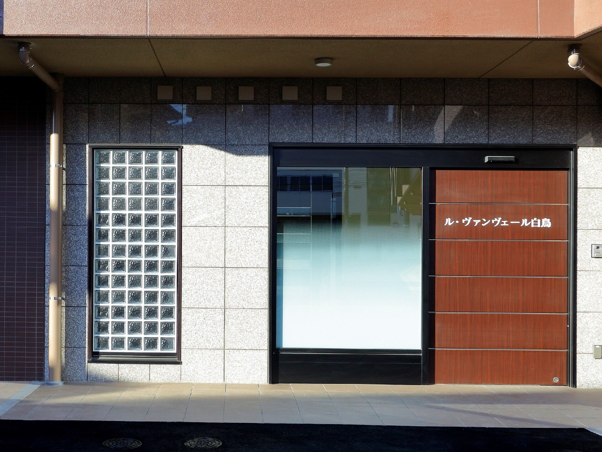 段差のないエントランス周辺。シンプルなブラウンのドアには白い文字でホーム名が書かれている。