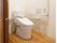 ひもが付いたオレンジの呼び出しボタンや手すりが付いたトイレにはスライド式のドアが設置されている。