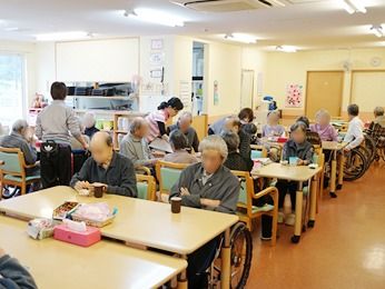 食事をとるための広めのホールの様子。高齢者が座ってくつろいでいる写真